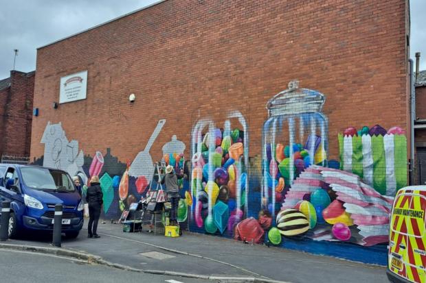 Andy O'Rourke at work on his latest mural, an ode to the historic Pells sweets factory.