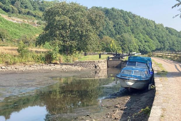 A boat lies in the dried up Huddersfield narrow canal near Linthwaite