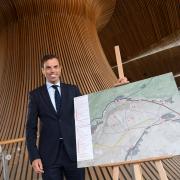 Economy and Transport Minister Ken Skates with a map of the proposed layout of the Global Centre of Rail Excellence. Credit: Welsh Government