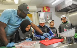 Tony Ogunsulire, Director of Steps4Change, at the Butetown Pavilion, leads a cooking class for children, teaching them life skills.